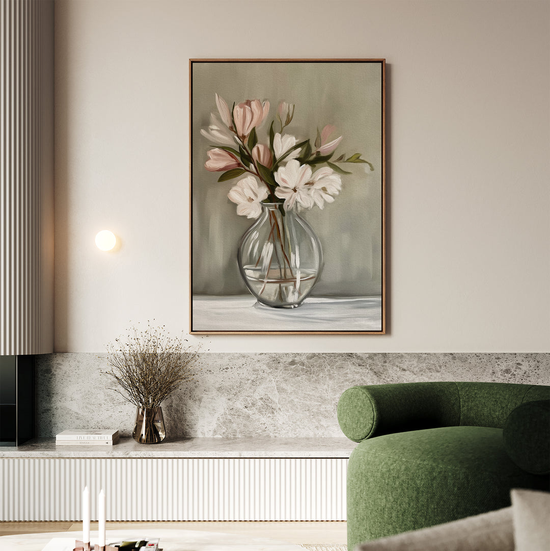 A modern living room with a green armchair, marble bench, and framed Vase & Grace Canvas Art featuring minimalist white and blush flowers in a glass vase on a light-colored wall.