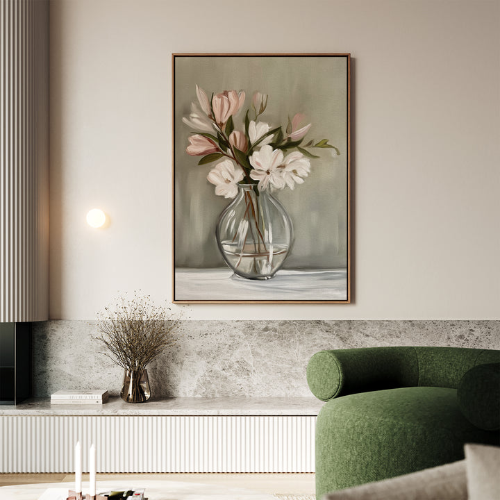 A modern living room with a green armchair, marble bench, and framed Vase & Grace Canvas Art featuring minimalist white and blush flowers in a glass vase on a light-colored wall.
