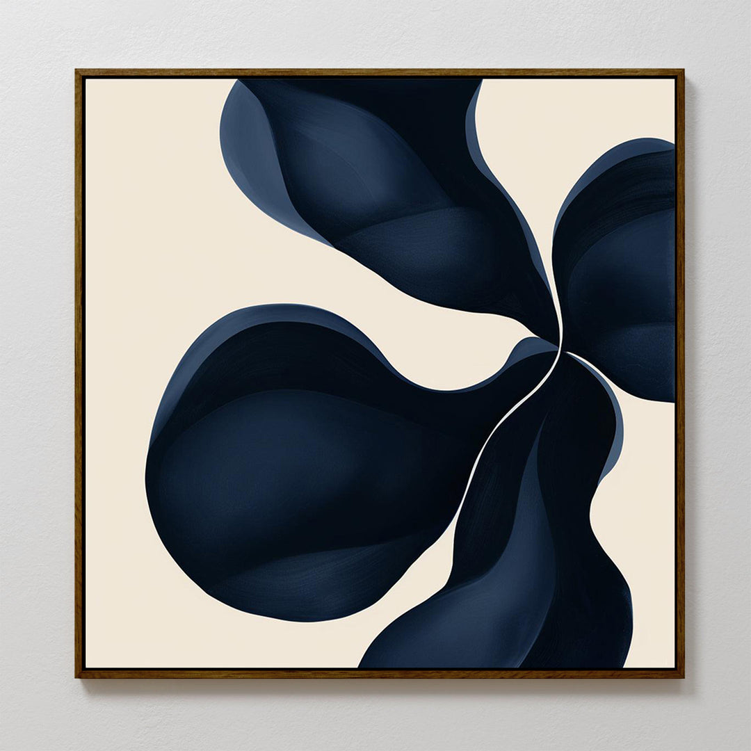 Blossom Blue Abstract Canvas Art features four large, dark blue petal-like shapes on a light beige background. This minimalist print is framed in a thin, dark frame and is displayed on a white wall.