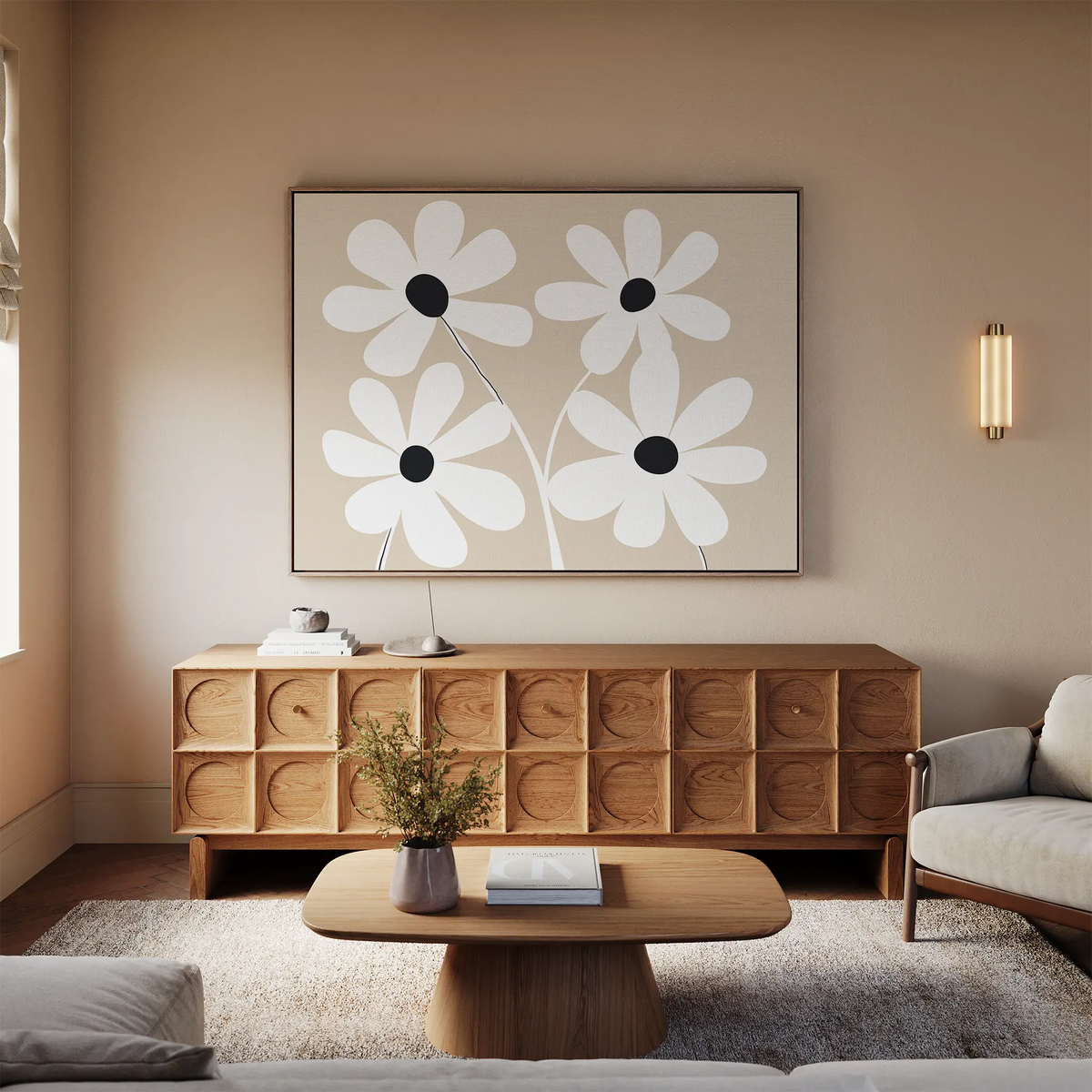 A modern living room features a wooden sideboard, coffee table, and light sofa. Above the sideboard hangs the White Blooms Canvas Art; a sconce, books, and a vase add decorative touches.