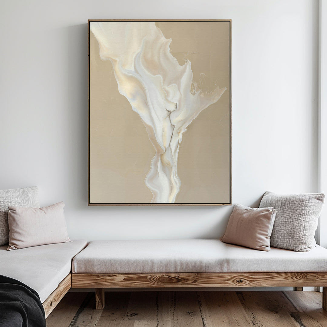 A minimalist living room with light wood furniture, beige and white cushions, and the White Flame Abstract Canvas Art featuring flowing cream and white shapes on a tan background hanging on the wall.