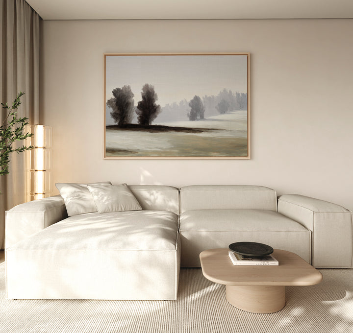 A modern living room features a light beige sectional sofa, a low wooden coffee table, and the Winter Dusk Canvas Art as minimalist wall decor. Natural light flows through tall windows with sheer curtains, highlighting the neutral tones.