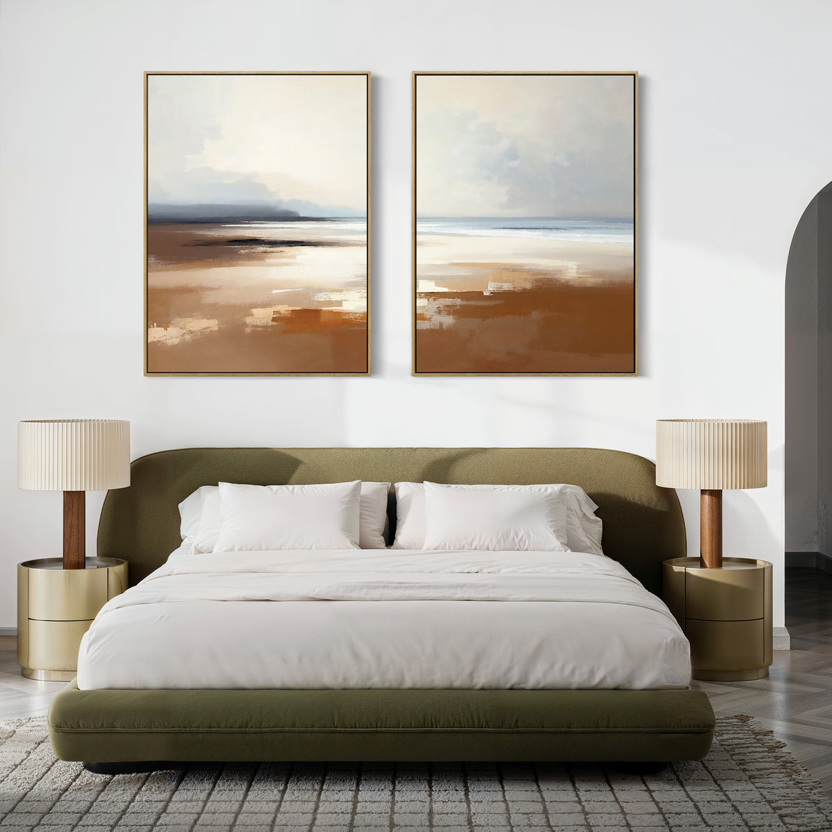 A modern bedroom with an olive green bed, white bedding, two round nightstands with beige lamps, and tranquil "Amber Shore - Set Of 2" abstract landscape paintings above the headboard. The room features a neutral color palette.