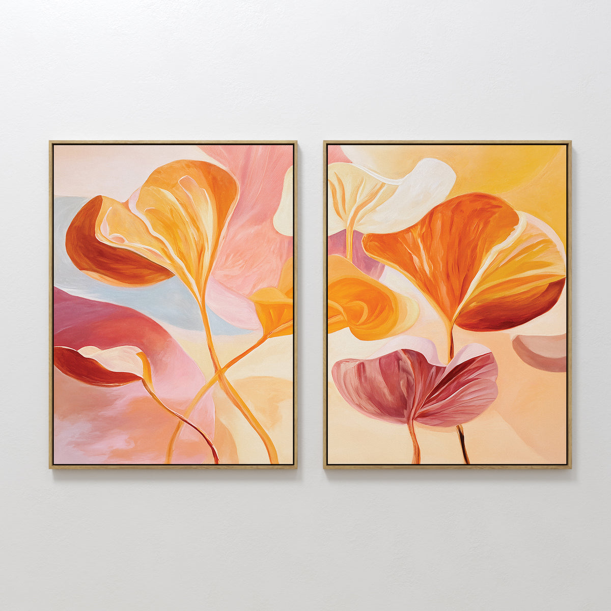 The Autumn Reverie - Set of 2 features framed abstract botanical prints with large overlapping leaves in warm orange, pink, yellow, and cream tones on a light background, displayed side by side on a white wall.