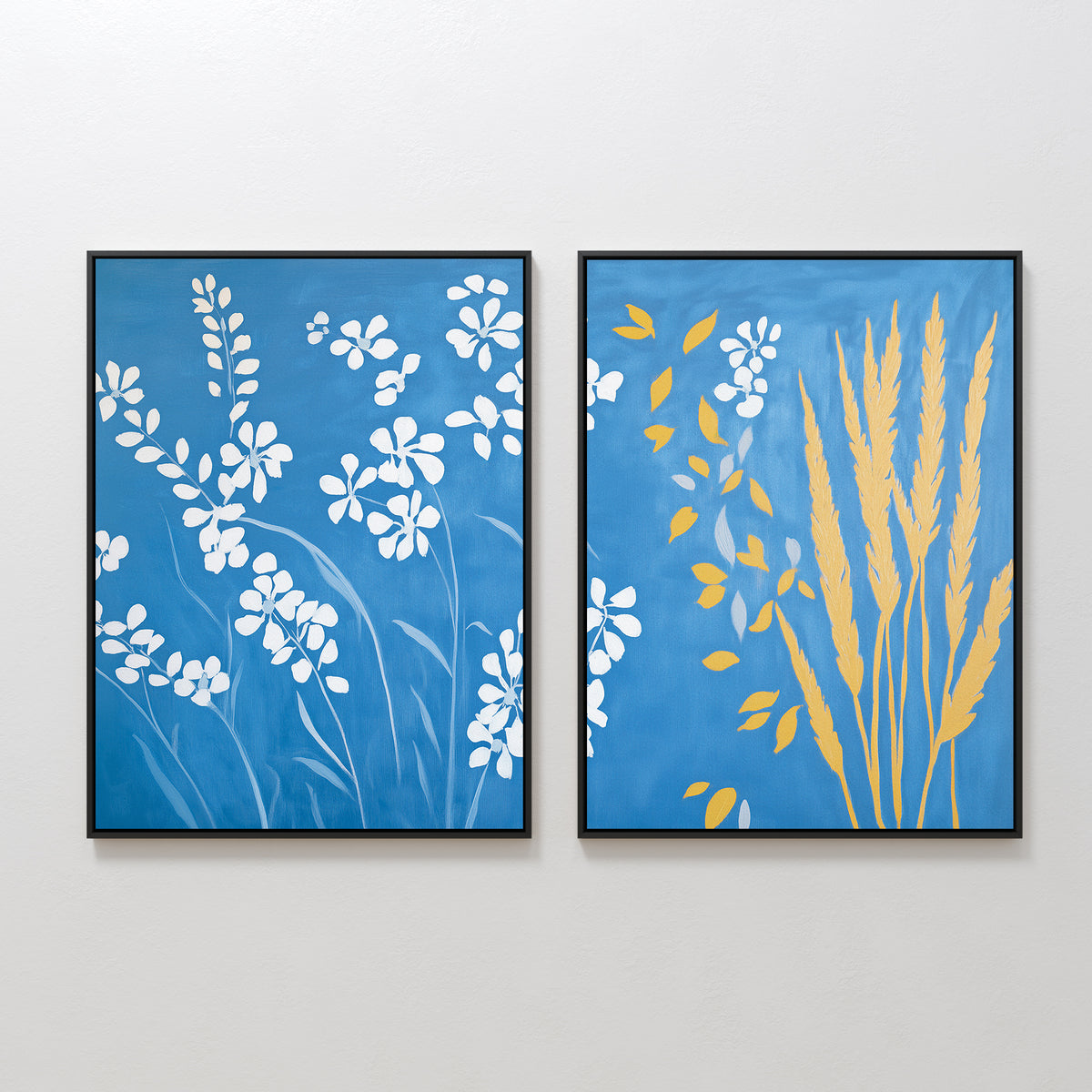 The Azure Meadow - Set of 2 features two framed artworks: one with white wildflowers and leaves on a blue background, and the other showing yellow wheat stalks and foliage inspired by a Nordic park, both displayed on a white wall.