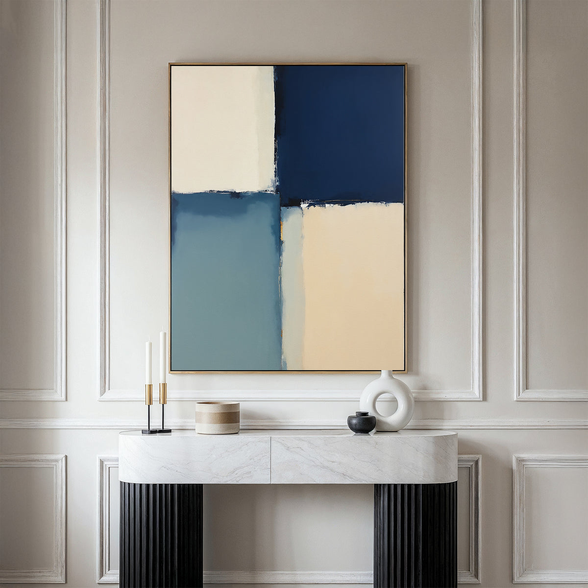 A modern console table with decorative objects sits against a paneled wall, topped by the Blue Quarters Canvas Art - Vertical, featuring a blue, cream, and beige geometric design—an ideal accent for modern living rooms.