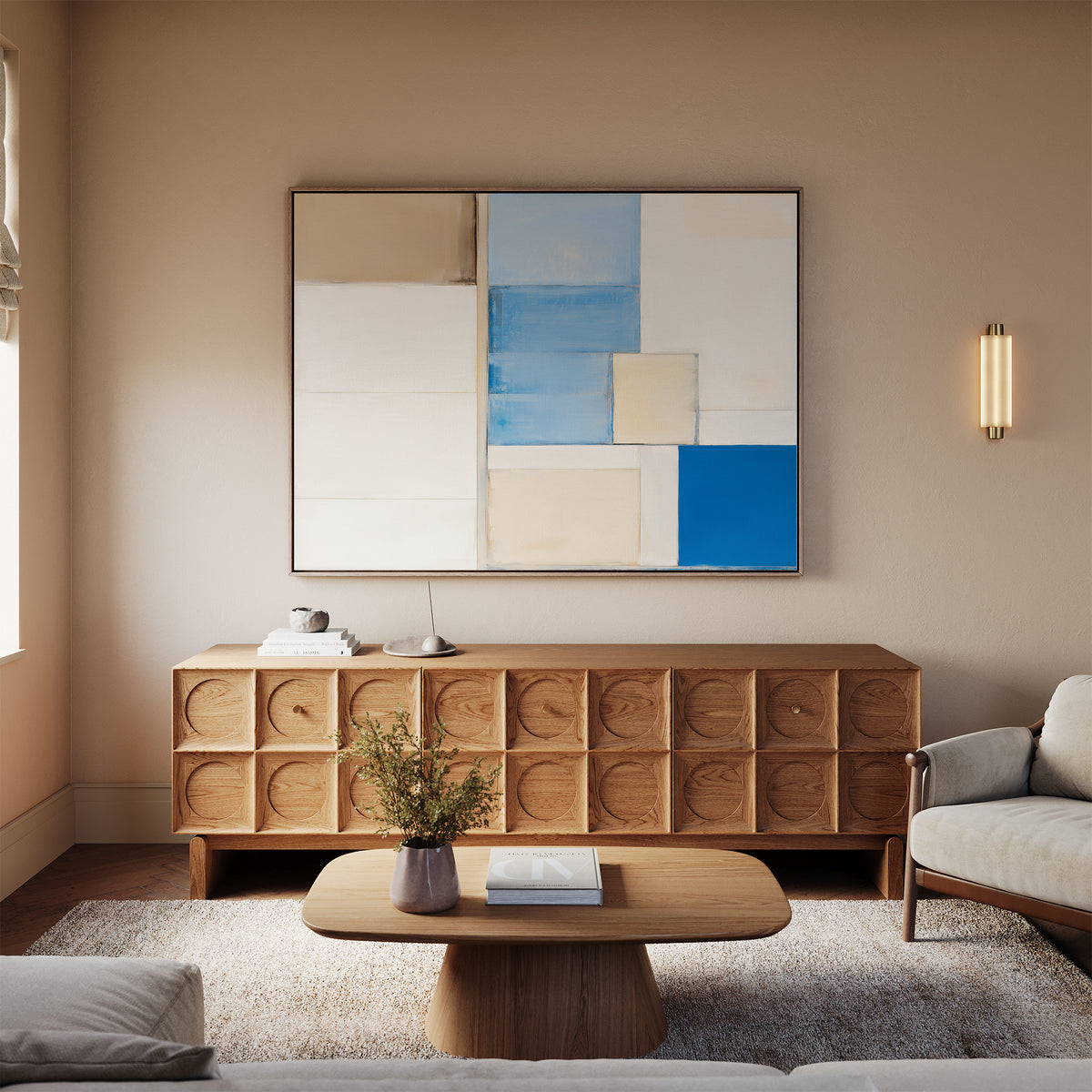 A modern living room features a light wood coffee table, textured wooden sideboard, beige sofa, soft rug, and the Blue Tiles Composition Canvas Art - Horizontal in blue, beige, and white tones for a stylish touch above the sideboard.