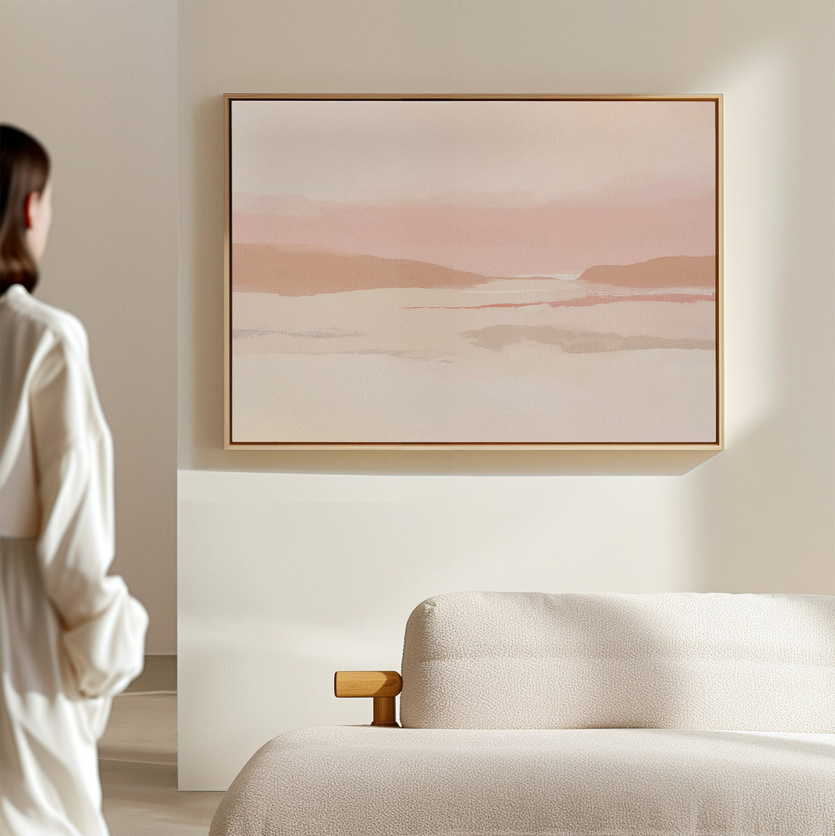 A person stands in a minimalist room facing the Blush Mesa Canvas Art - Horizontal above a cream sofa, creating an inviting earth-toned decor.