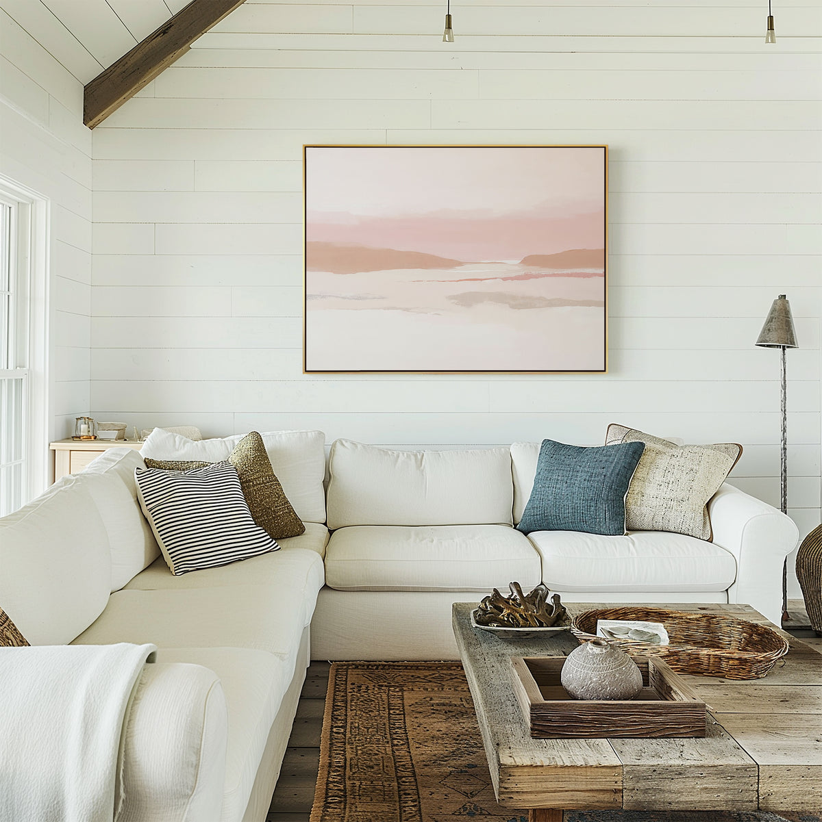 A cozy living room with white shiplap walls, a large white sectional sofa, assorted throw pillows, rustic wooden coffee table, and the Blush Mesa Canvas Art - Horizontal above the sofa completes this earth tone decor.