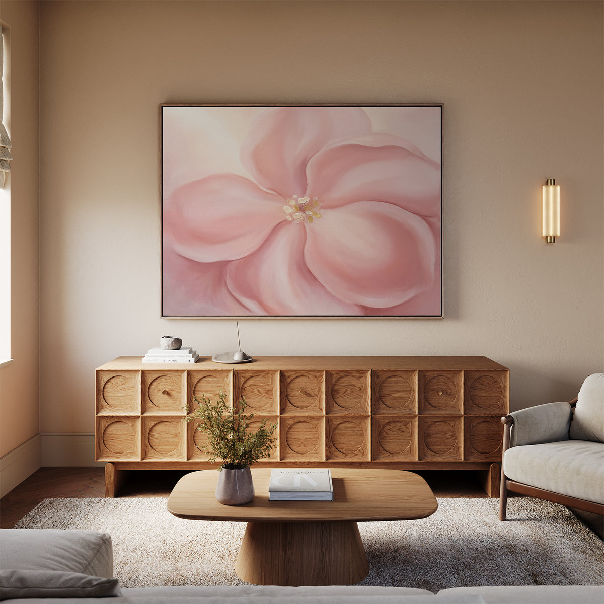 A cozy living room features a modern wooden coffee table, textured sideboard, and the Blushing Magnolia Canvas Art - Horizontal above a light sofa, with neutral walls and a flower vase on the table for soft romantic charm.