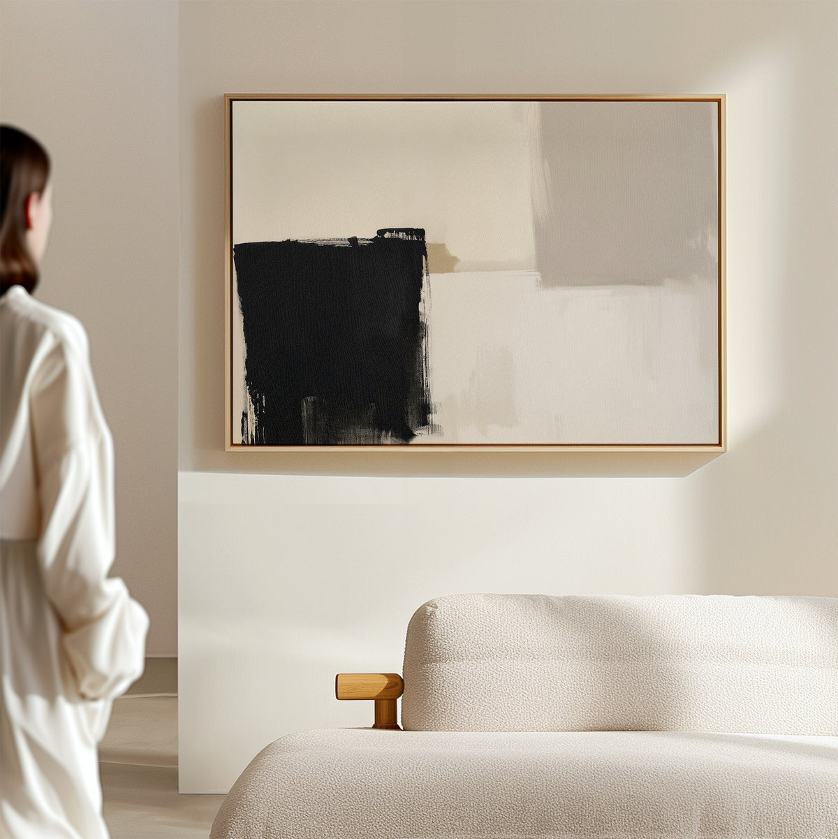 A person stands in a minimal, modern living room featuring a textured beige sofa and the Bold Division Canvas Art - Horizontal in black, white, and gray on the wall.