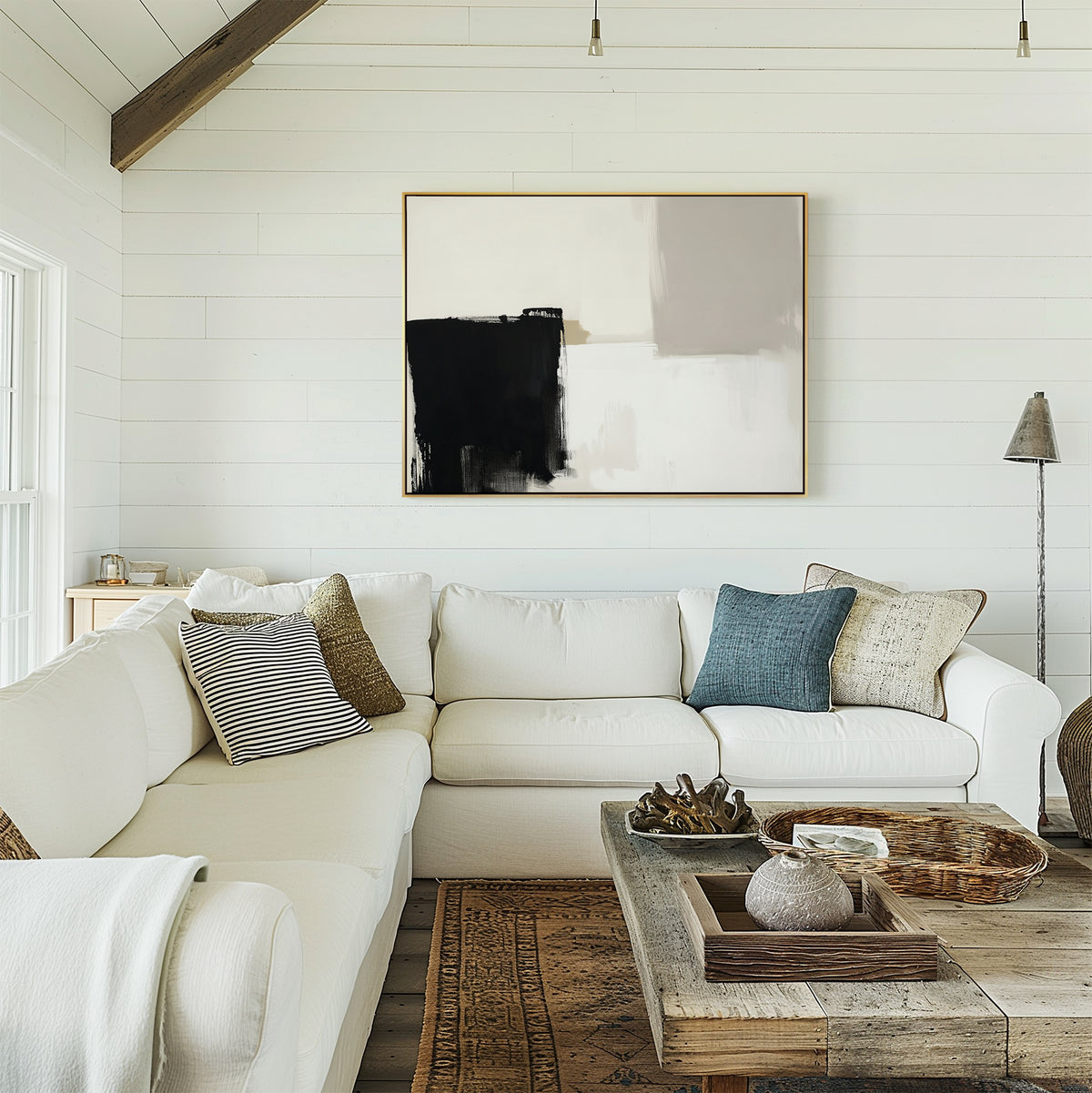 A cozy living room with white shiplap walls, a large sectional sofa with assorted throw pillows, a rustic wooden coffee table, and the Bold Division Canvas Art - Horizontal hanging above the couch.