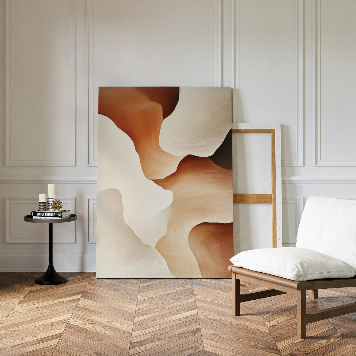 A minimalist room with herringbone wood floors, a white cushioned chair, a round black table with candles, and the Canyon Curves Canvas Art - Vertical in beige and brown tones leaning against a white paneled wall—ideal for modern spaces.