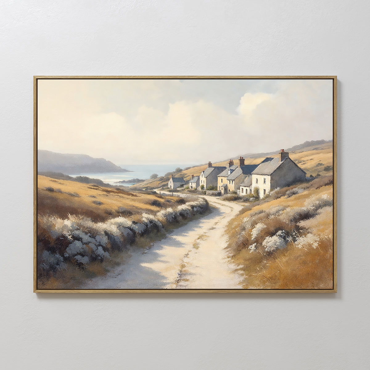 Bring coastal charm to your home with the Coastal Haven Canvas Art - Horizontal, featuring a rustic landscape of a winding dirt road, white cottages with red roofs, golden fields, distant hills, and a serene sea under a cloudy sky.