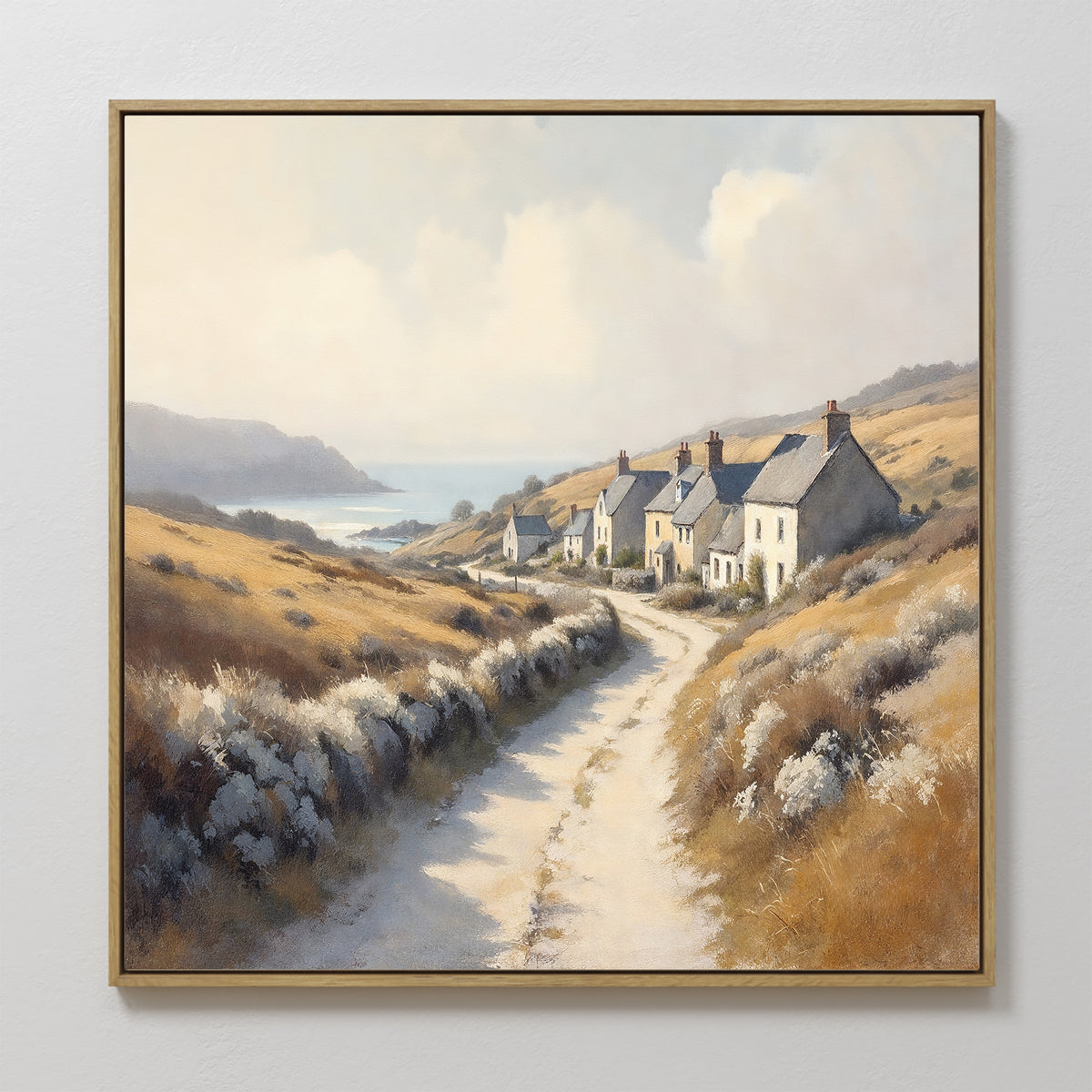 The Coastal Haven Canvas Art - Square features a scenic dirt road to seaside cottages, golden fields, rolling hills, and a bright sky—ideal rustic wall decor for any space.
