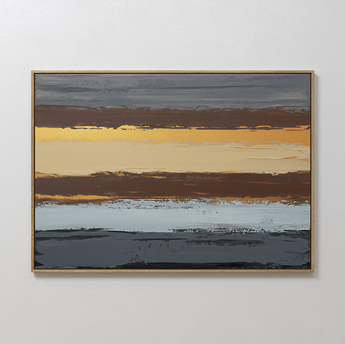 The Coastal Strata Canvas Art - Horizontal features abstract horizontal bands in gold, brown, blue, and gray with textured brushstrokes. Set in a thin gold frame and mounted on a white wall, it brings earthy sophistication to any setting.