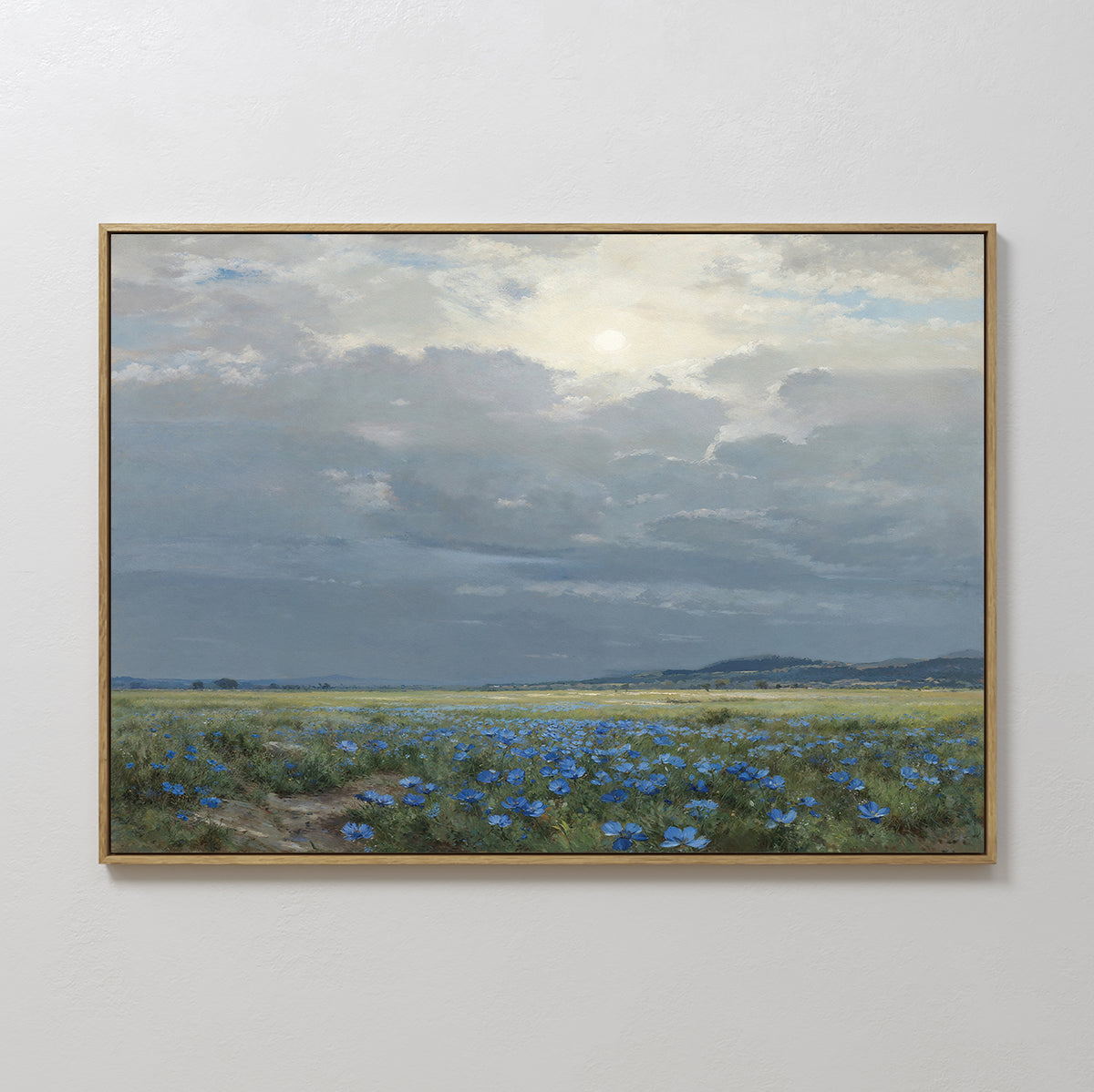 The Cornflower Fields Canvas Art - Horizontal showcases blue wildflowers under a cloudy sky with sunlight and distant hills, making it ideal pastoral wall art for countryside-inspired home decor.