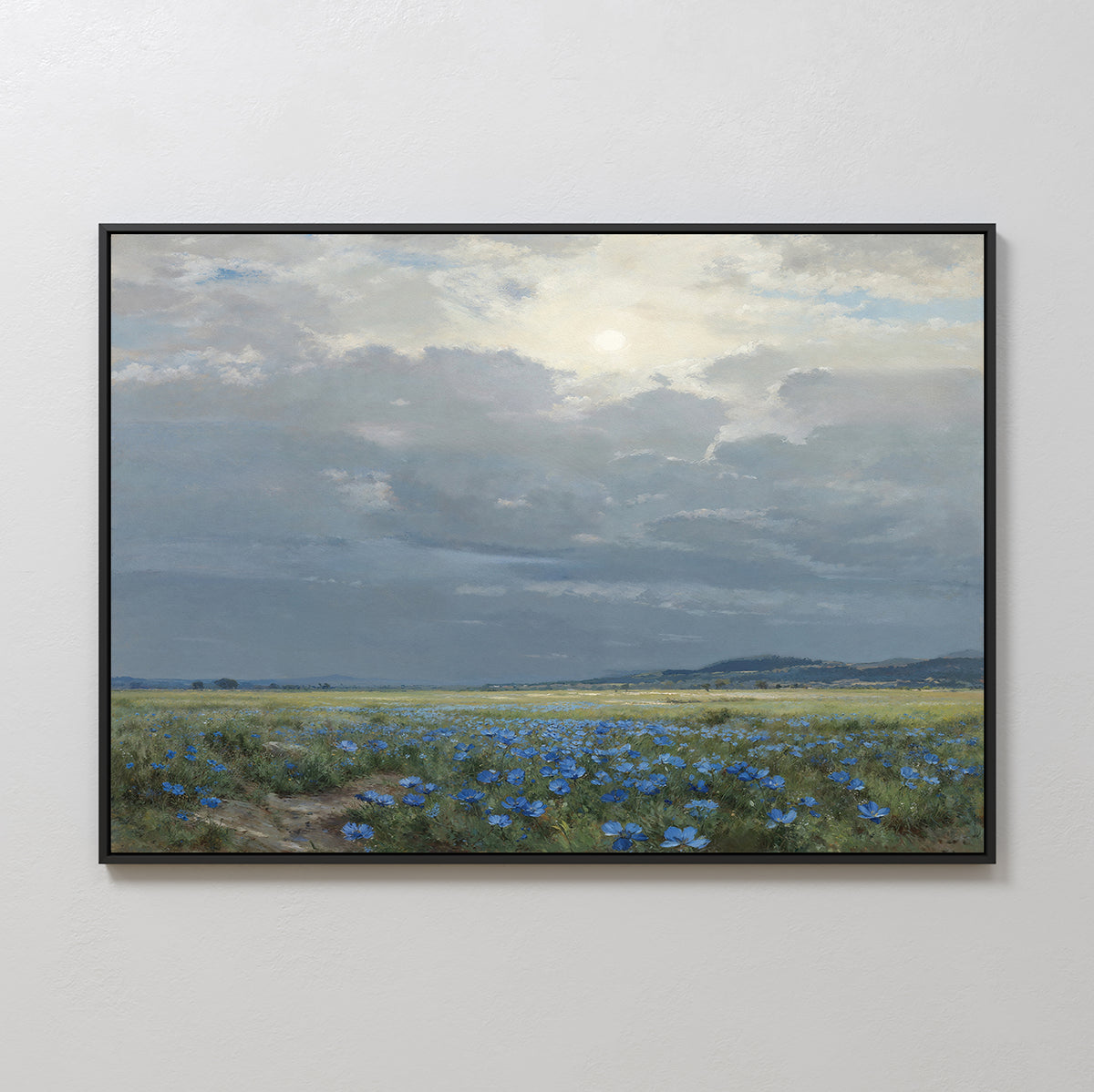Cornflower Fields Canvas Art - Horizontal features a scenic field of blue wildflowers below a cloudy, sunlit sky. Displayed on a plain white wall, it's perfect countryside home decor.