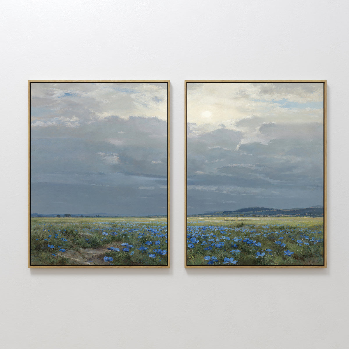 The Cornflower Fields - Set of 2 features framed canvas prints showing tranquil cornflower fields beneath a cloudy sky and distant hills, capturing a calm, expansive landscape with soft light.