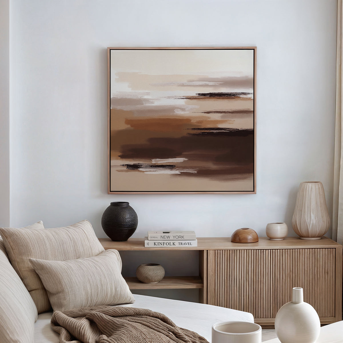 A modern living room with a beige sofa, wooden sideboard, and vases is enhanced by the Desert Winds Canvas Art - Square in brown and cream tones—ideal for those who love earth tone wall art.