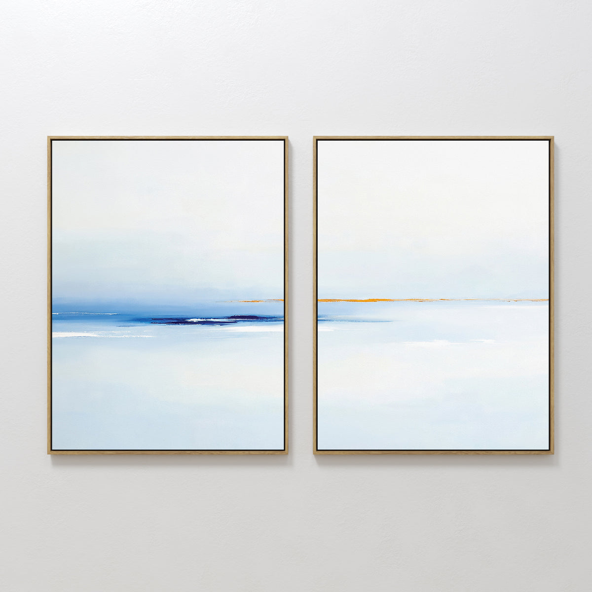 The "Distant Archipelago - Set Of 2" features minimalist prints in gold frames, each with serene blue, white, and beige seascapes—ideal contemporary wall art for a calming and tranquil atmosphere.