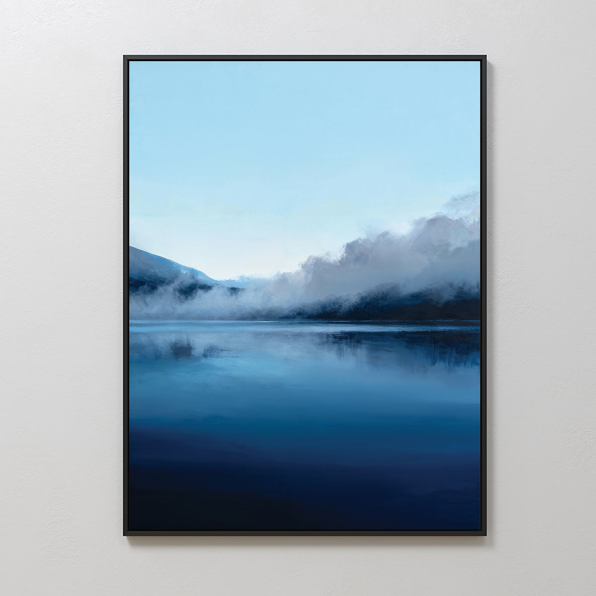 The Fjord Mist Canvas Art - Vertical features a serene lake with rising mist and mountains in soft blue and dark tones, adding Nordic charm to your space. This tranquil wall art looks stunning against a plain white wall.