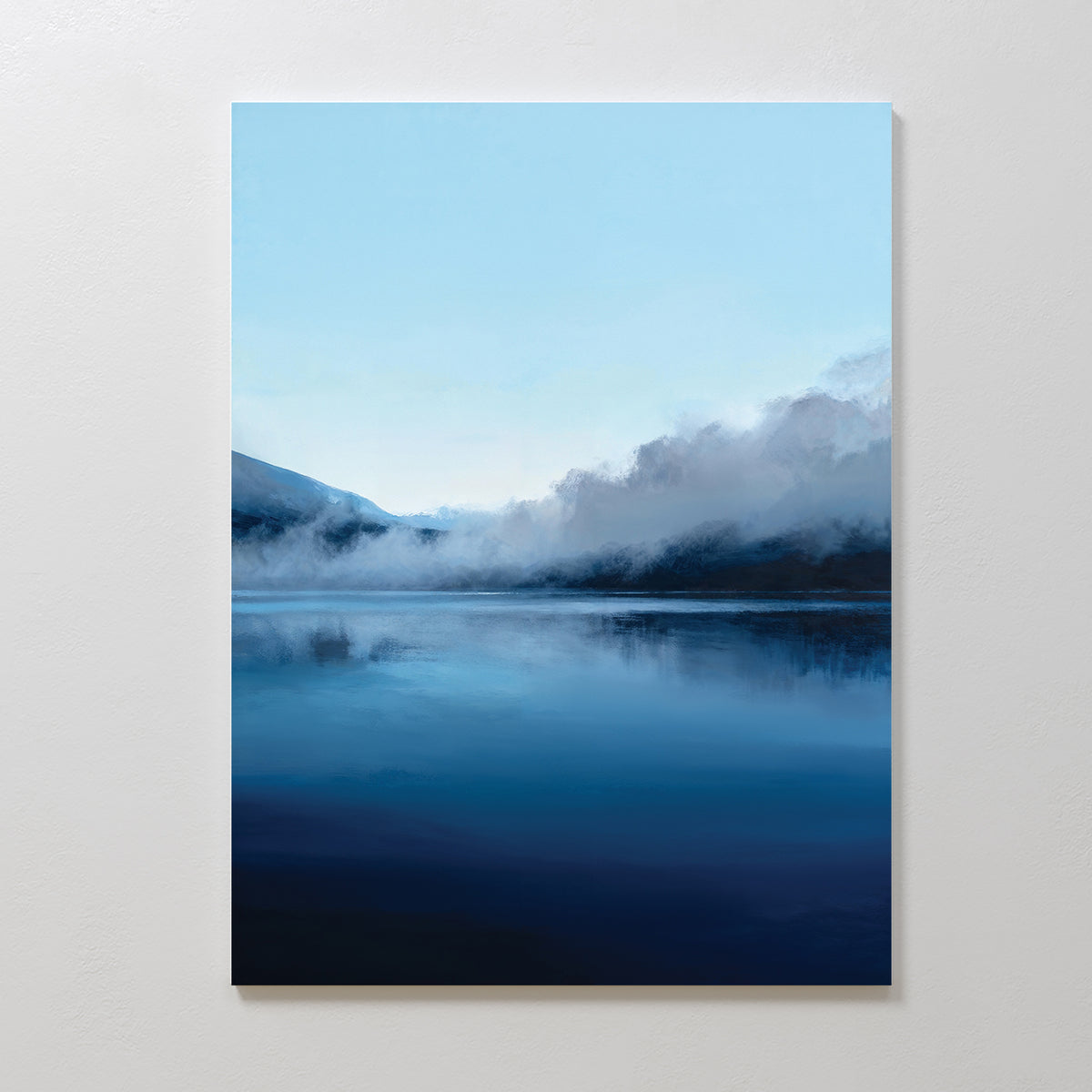 The Fjord Mist Canvas Art - Vertical features a serene lake reflecting the blue sky and distant mountains under a gentle mist, creating tranquil wall art ideal for Nordic decor on any plain white wall.