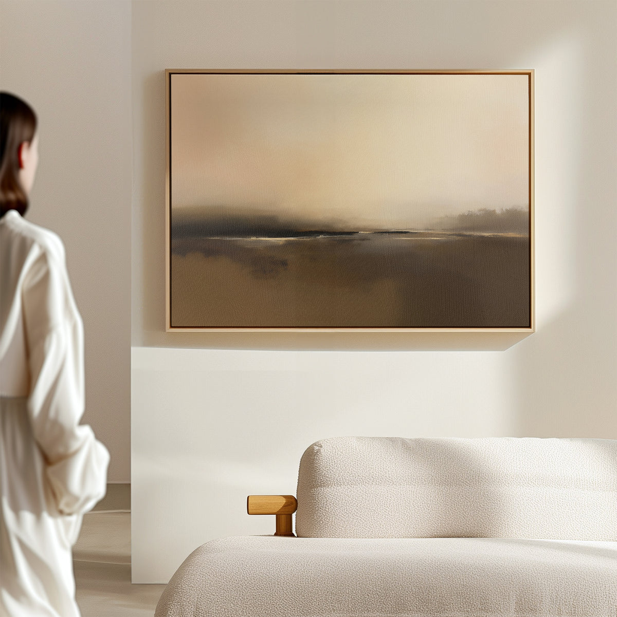 A person stands in a minimal, light-filled room with a beige sofa and the "Foggy Beach Expanse Canvas Art - Horizontal" hanging on the wall.