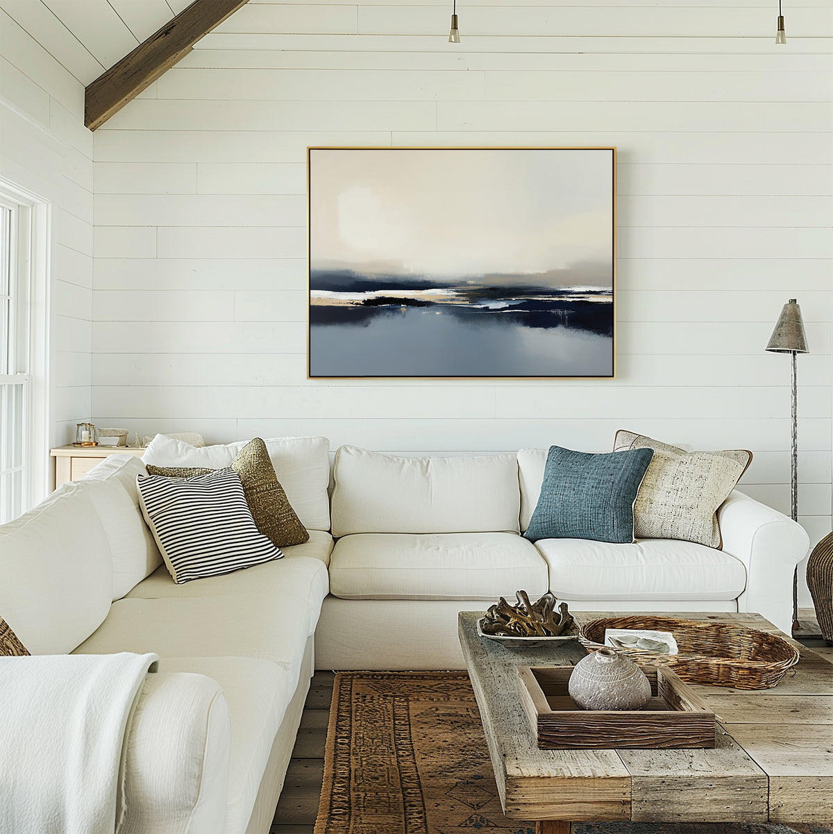 A bright, modern living room with white shiplap walls, a white sectional with assorted pillows, a wooden coffee table, and the Frozen Bay Canvas Art - Horizontal displayed above the sofa.