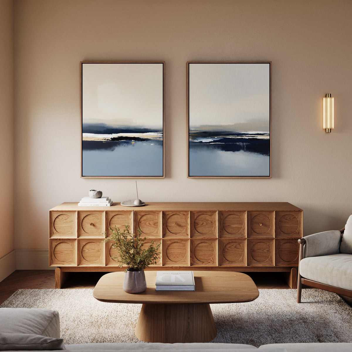 A modern living room features a wooden coffee table, matching sideboard, light sofa, and the Frozen Bay - Set Of 2 artworks above. A vase with greenery sits on the table; soft lighting enhances the cozy modern decor.