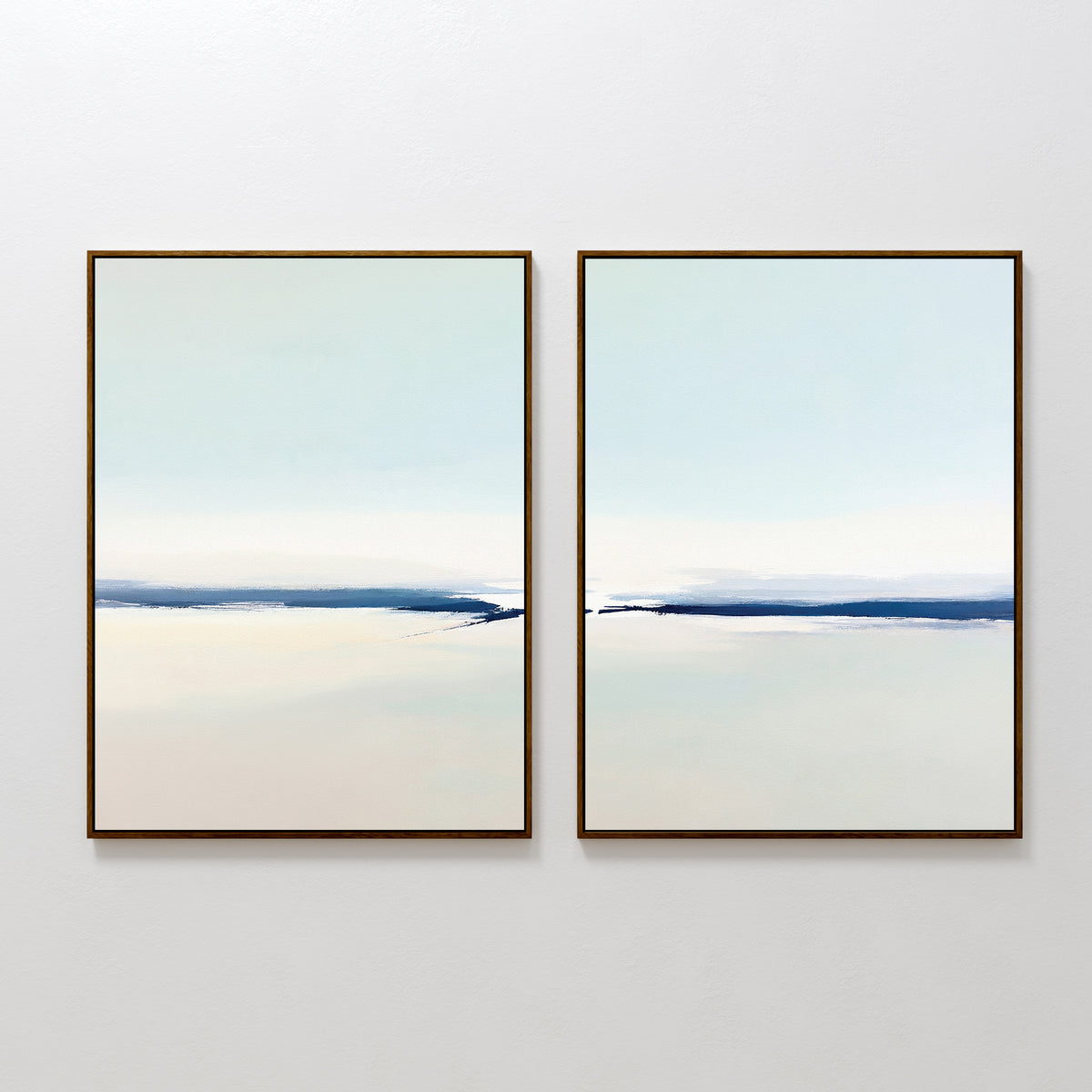 Frozen Channel - Set Of 2 features minimalist art prints with soft cream and light blue gradients, accented by a dark blue horizontal line. Simple, thin frames complete this serene decor set, ideal for modern living rooms.