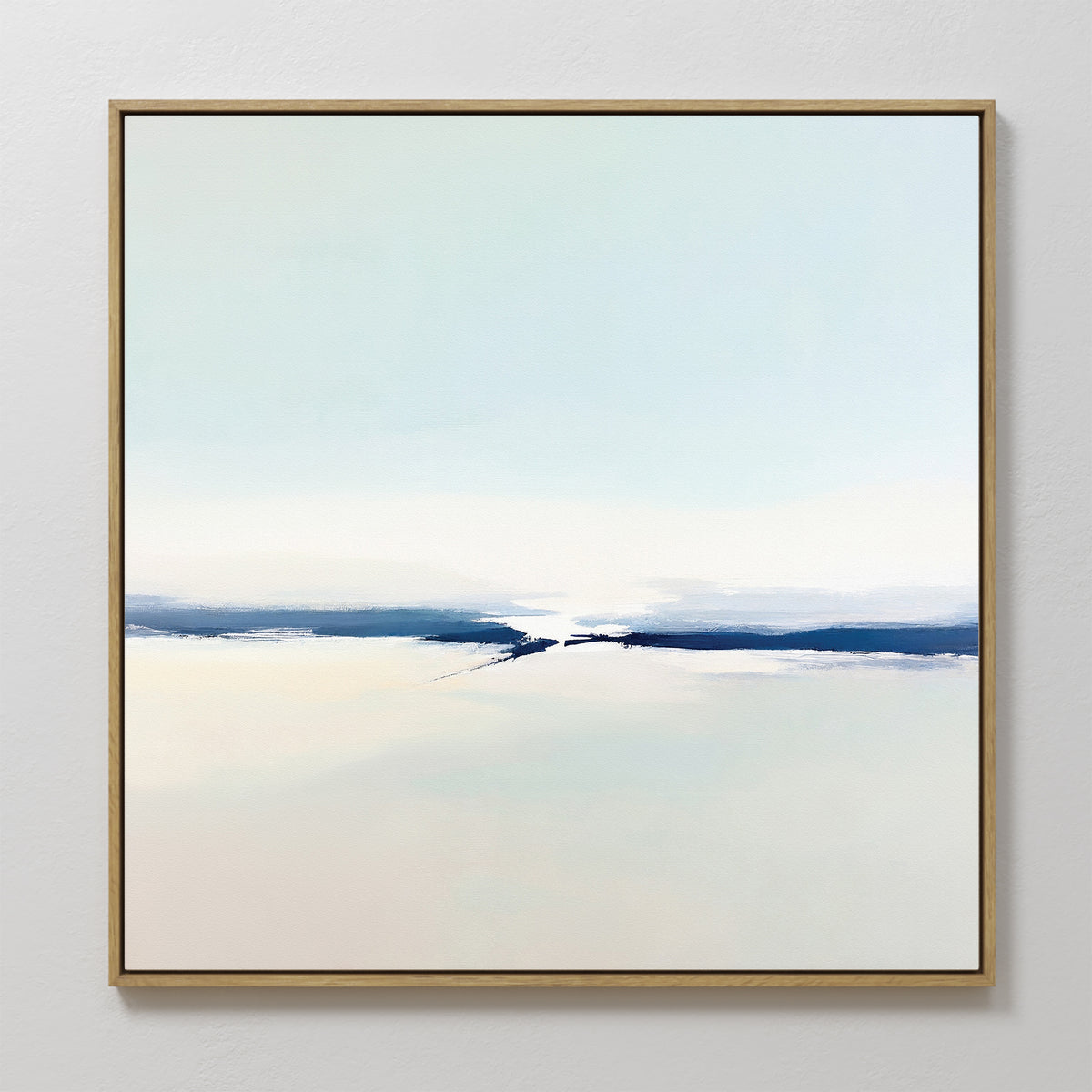 Frozen Channel Canvas Art - Square features a minimalist abstract design in soft, pale hues. A horizontal dark blue and white band suggests a distant horizon, all set against a light background and framed in gold—ideal for modern living rooms.
