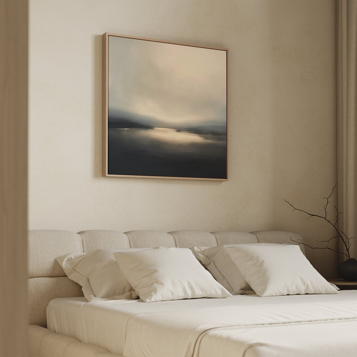 A modern bedroom with a beige upholstered bed, white pillows, and tidy bedding. Above the bed hangs Golden Fog Horizon Canvas Art - Square. A bare branch sits on a side table near light-colored curtains.