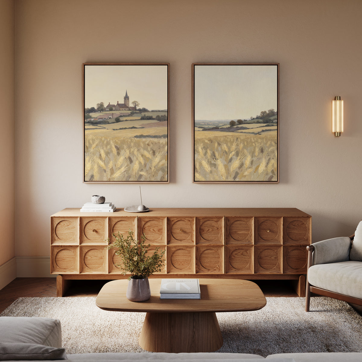 A cozy living room features a wooden coffee table, a textured sideboard, neutral furniture, and the Harvest Chapel - Set of 2 canvas prints. A small plant and warm lighting add rustic charm for a calm, inviting atmosphere.
