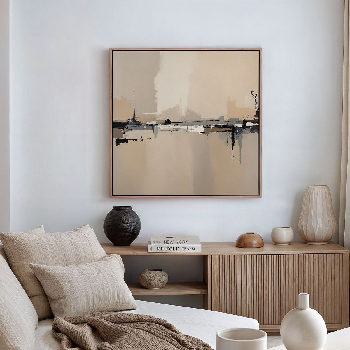 A modern, minimal living room features a light sofa, neutral cushions, and a wooden sideboard. The Industrial Cityscape Canvas Art - Square hangs above, while decorative vases and books complete the cozy decor.