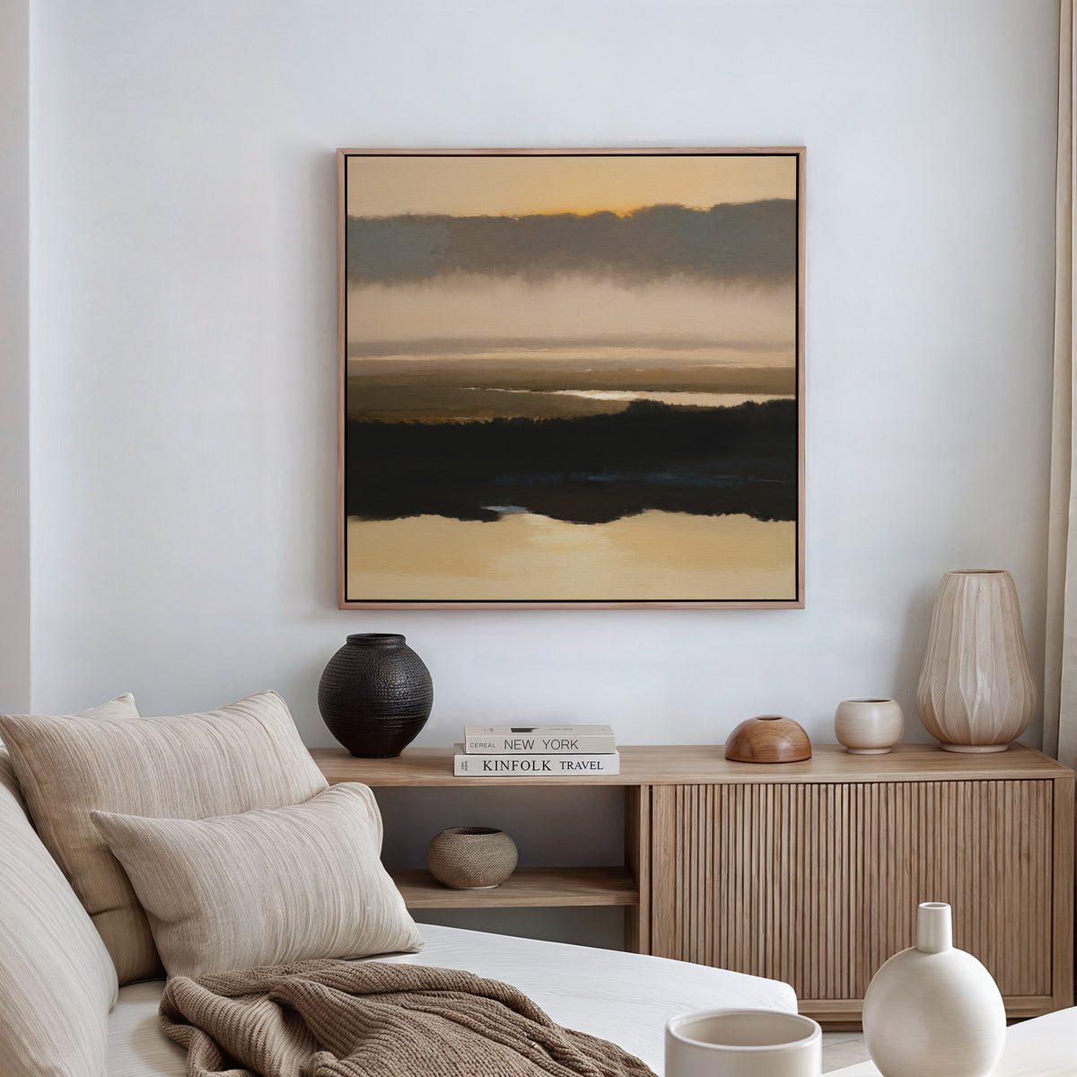 A minimalist living room features a beige sofa, wooden sideboard with vases and books, and the Layered Valley Dawn Canvas Art - Square depicting an abstract landscape hanging on a white wall. Natural light streams in through curtained windows.