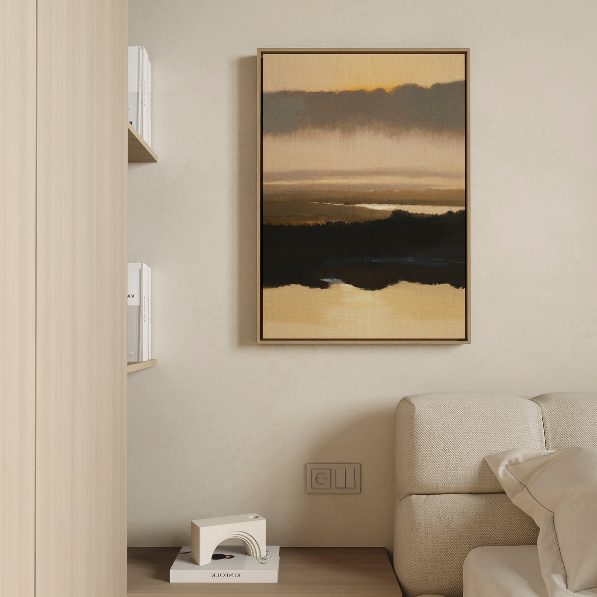 A minimalist living room features a beige sofa, a small white decor piece on a wooden floor, and the Layered Valley Dawn Canvas Art - Vertical—a framed abstract landscape with warm tones—hanging on a cream-colored wall. Bookshelves are partly visible on the left.