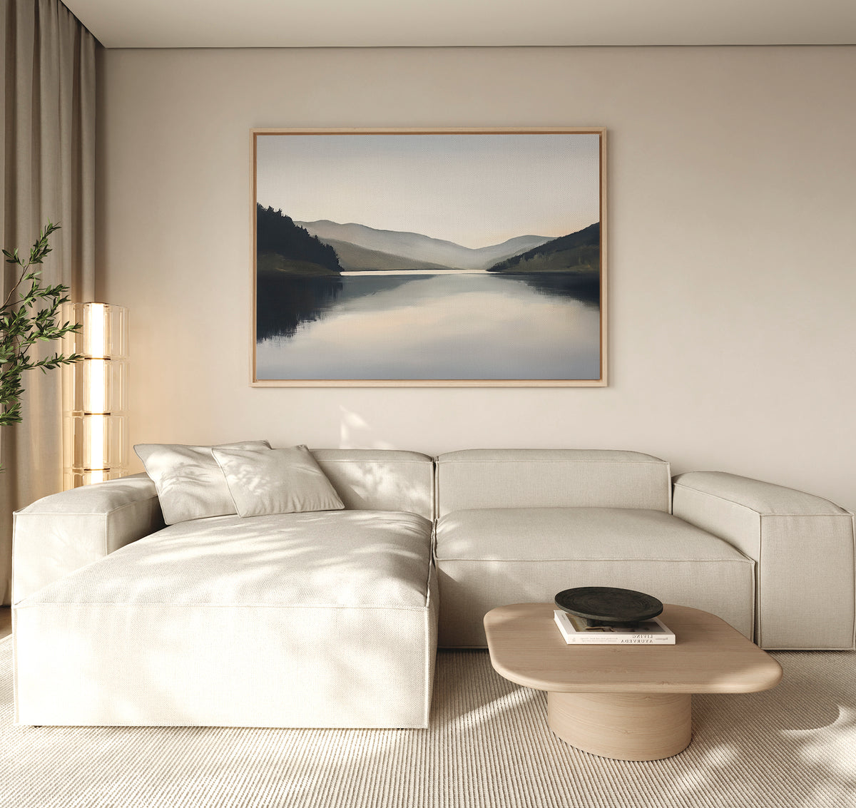 A modern living room with a light beige sectional, round wood coffee table, potted plant, and the Mirror Valley Canvas Art - Horizontal enhances the calm natural palette and minimalist decor.