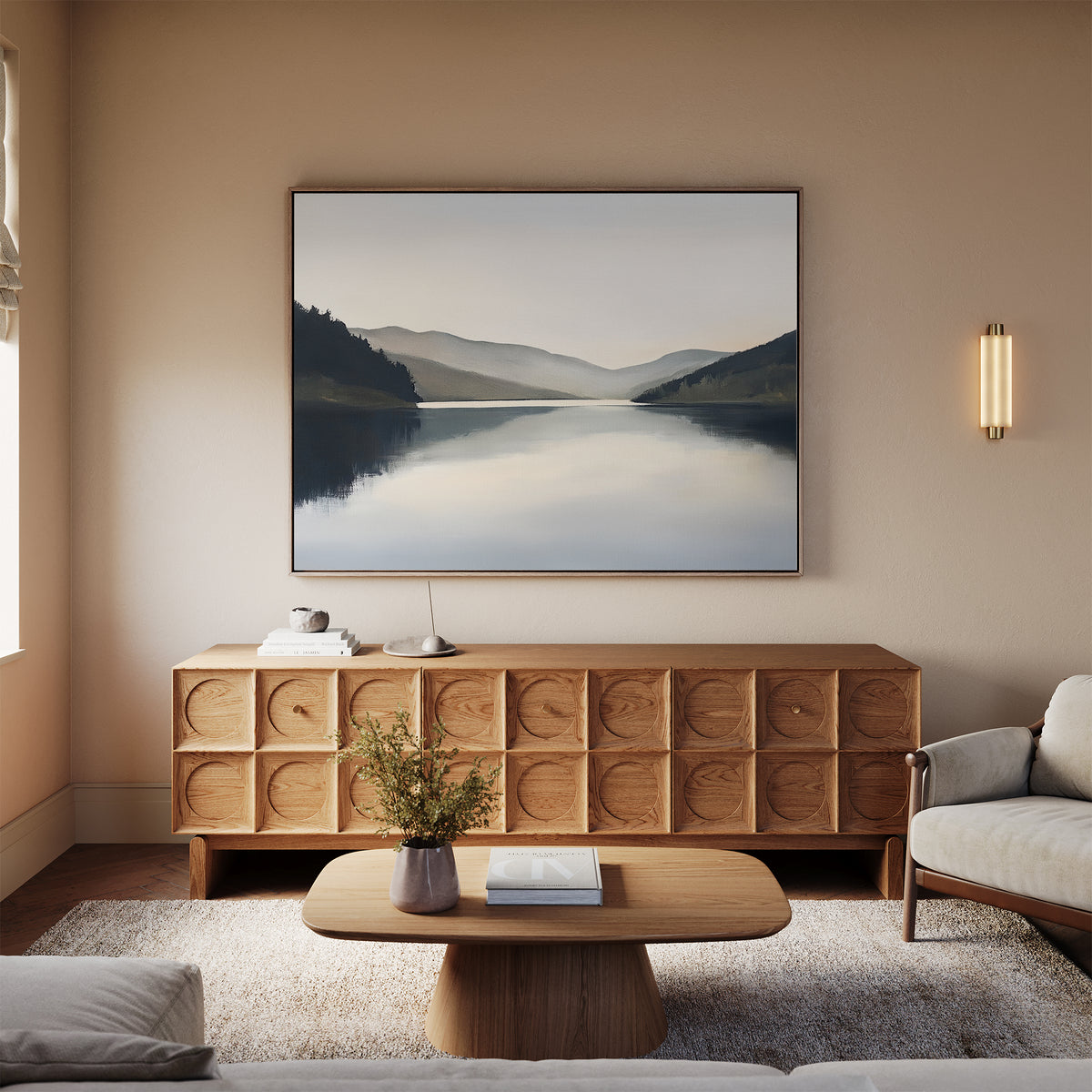 A serene living room featuring a light wood sideboard, modern coffee table, beige sofa, soft rug, wall-mounted light, and the Mirror Valley Canvas Art - Horizontal that enhances the calm natural palette of the space.