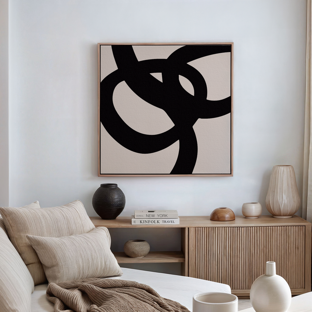 A modern living room with a beige sofa, neutral pillows, a wooden sideboard with books and vases, and Monochrome Stream Abstract Canvas Art adding contemporary elegance to the space.