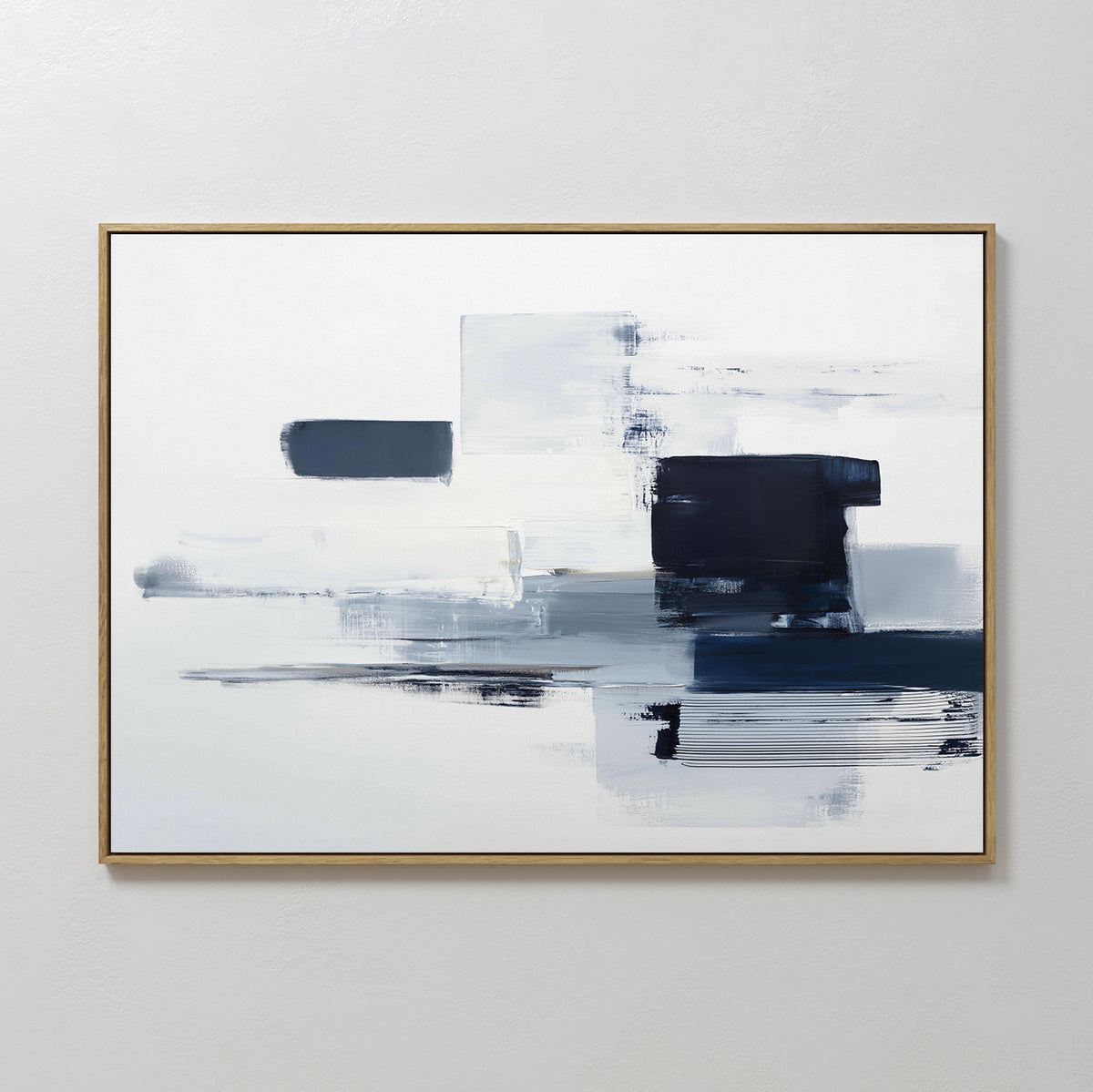 The Navy Brushwork Canvas Art - Horizontal showcases abstract geometric print with navy blue, gray, and white brush strokes on a mostly white background, highlighted by a thin gold frame—ideal modern wall art for any space.