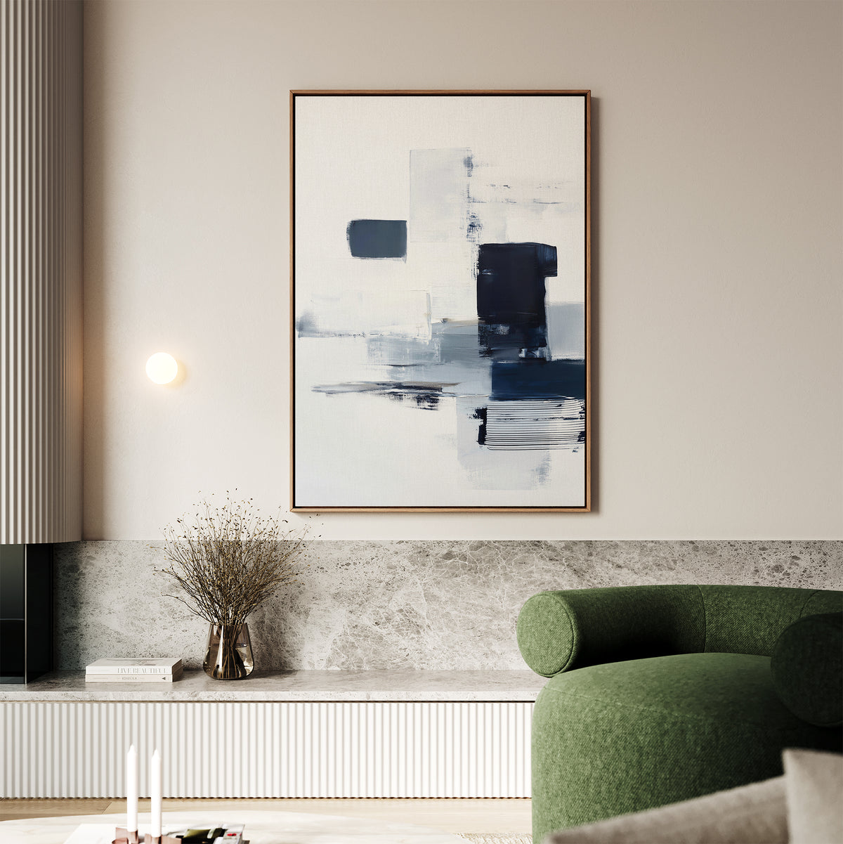 A modern living room featuring a green curved sofa, a marble ledge, dried flowers in a vase, and the Navy Brushwork Canvas Art - Vertical in blue, black, and white tones hanging on a light beige wall above.