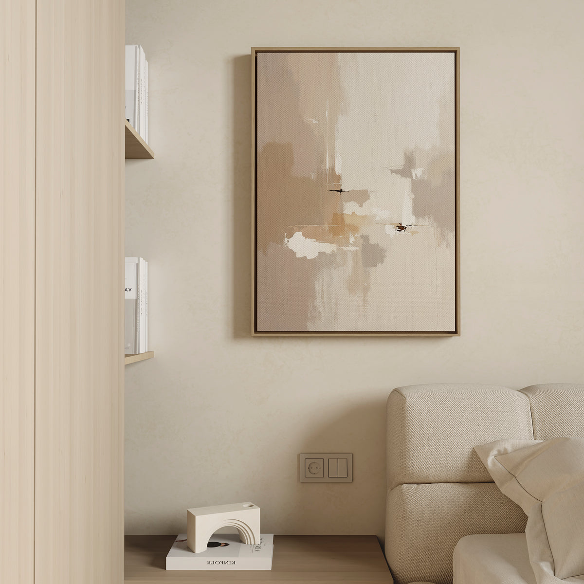 A minimalist living room corner features a beige sofa, books on a shelf, and the Neutral Territory Canvas Art - Vertical in neutral tones hanging on a light wall above a small floor décor—perfect for modern spaces.