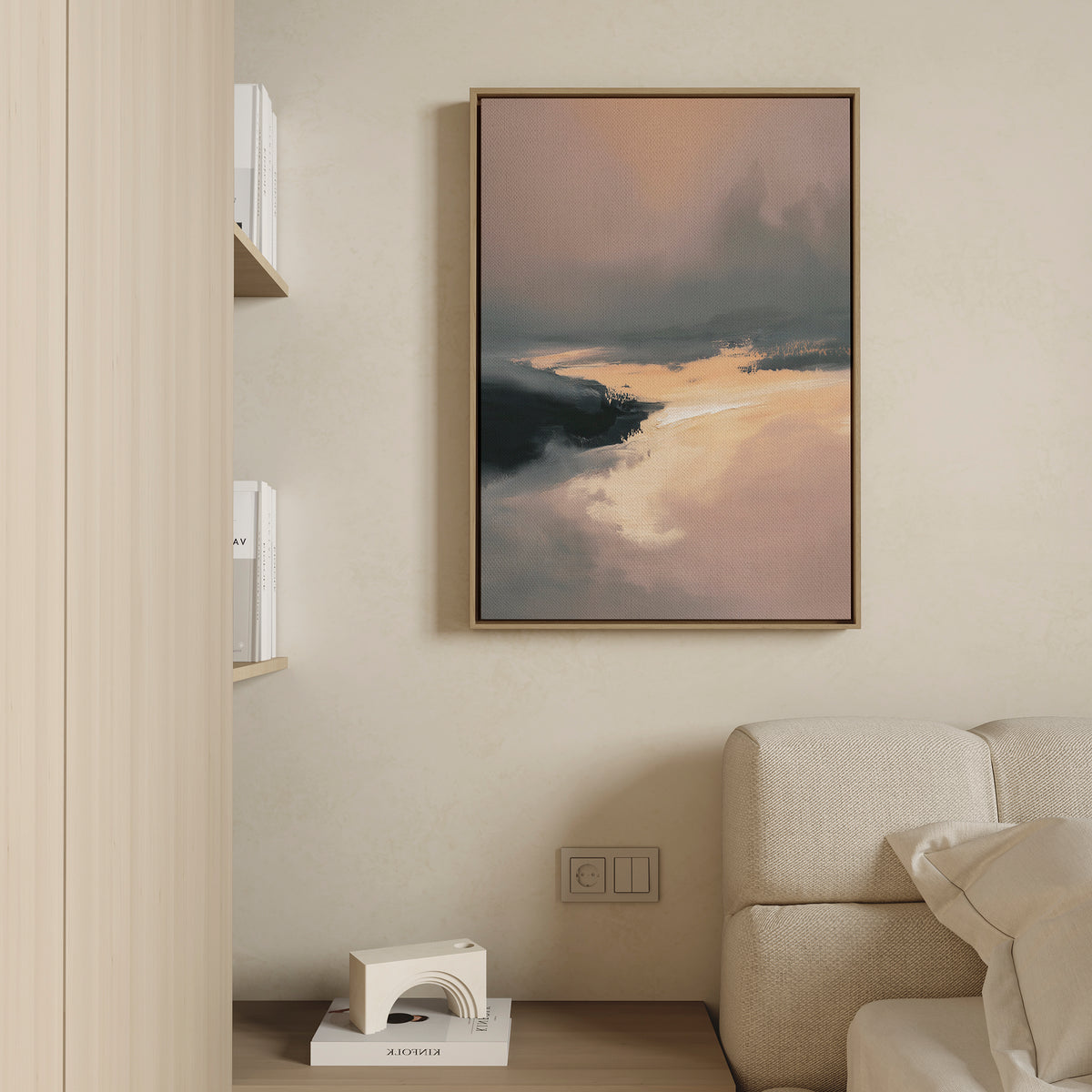 A modern living room features a beige sofa, a small shelf with books and decor, and the Nordic Fjord Canvas Art - Vertical, a framed landscape print in warm and dark tones displayed on a light-colored wall.