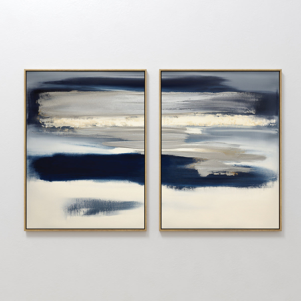The Northern Tides - Set Of 2 features abstract prints with wide horizontal brushstrokes in navy, beige, gray, and white, each framed in slim gold and displayed side by side on a white wall.