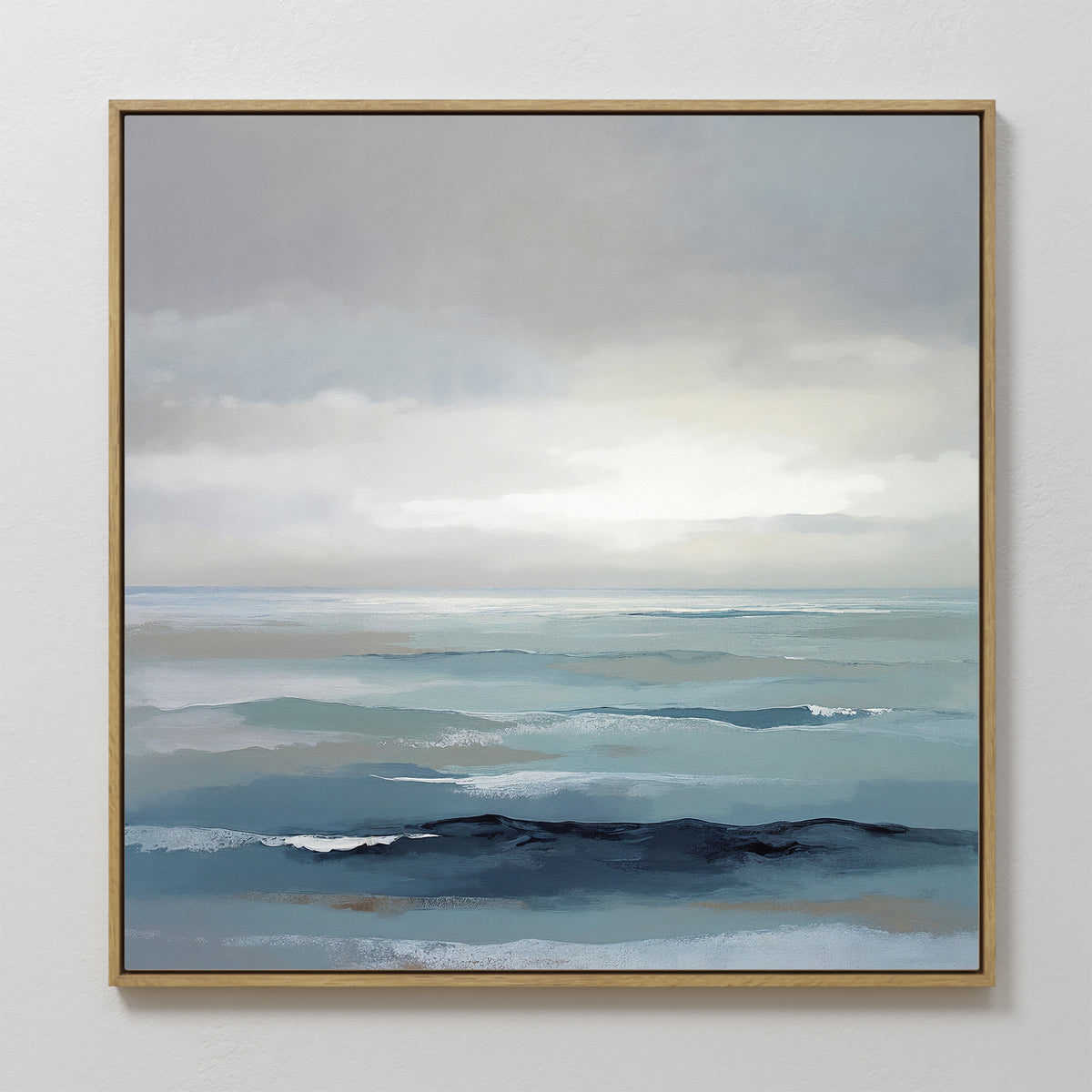 The Ocean Swells Canvas Art - Square features a framed coastal print of calm blue and gray waves under a cloudy sky, blending soft, muted tones for a tranquil, minimalist look—ideal serene wall art for any space.