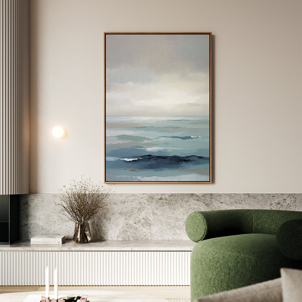 A modern living room with a green curved sofa and marble accents features the Ocean Swells Canvas Art - Vertical, an abstract seascape hanging on a beige wall above a shelf with dried flowers.