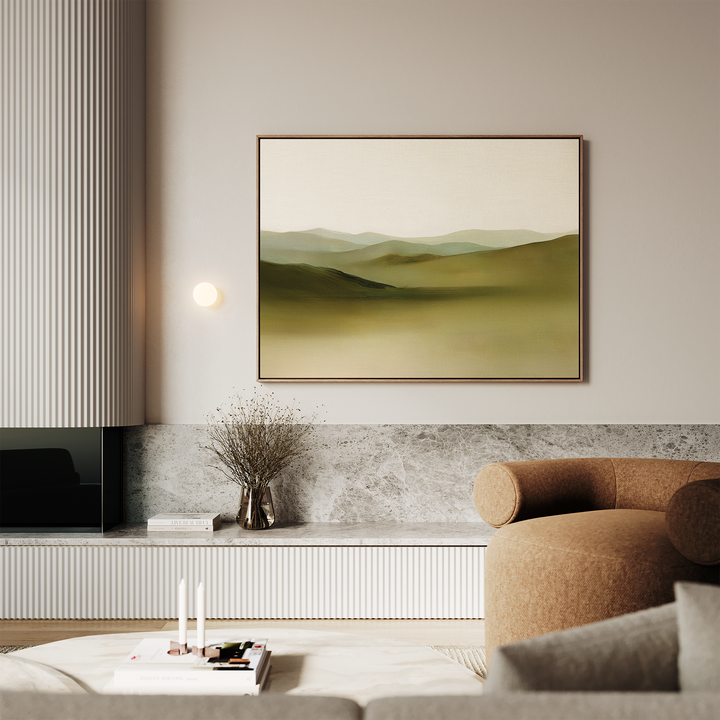 A modern living room with minimalist decor features a beige sofa, marble accents, a small round table with candles, a vase with dried branches, and the serene Pastoral Peace Canvas Art on the wall.