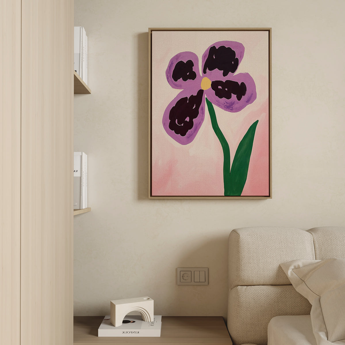 The Purple Pansy Canvas Art - Vertical, featuring a large abstract purple pansy with a green stem, hangs on a beige wall above a cream sofa in this modern minimalist living room, with a shelf of books and decor partly visible on the left.