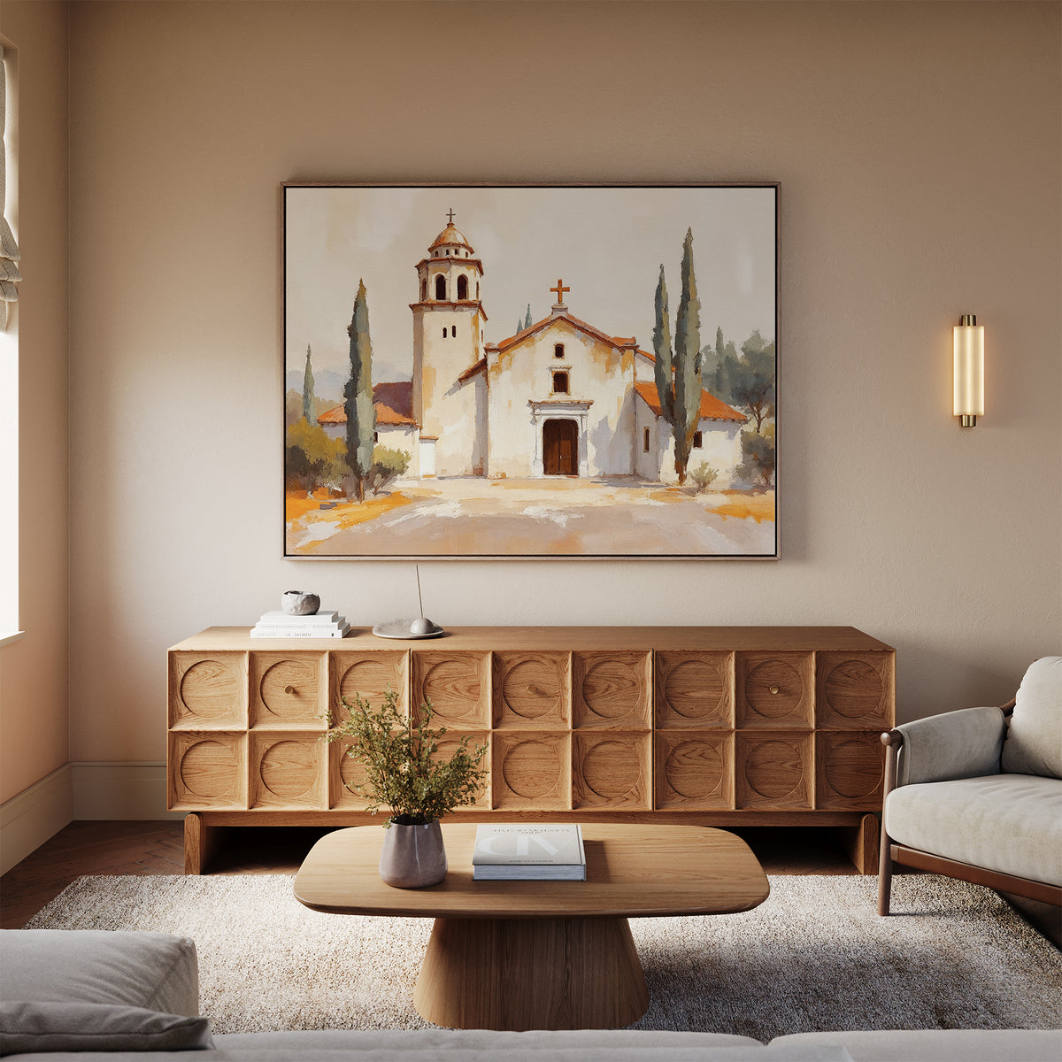 A cozy living room with neutral tones features a wooden sideboard, matching coffee table, light sofas, a soft rug, and the Sacred Courtyard Canvas Art - Horizontal depicting a Mediterranean church with cypress trees above the sideboard.